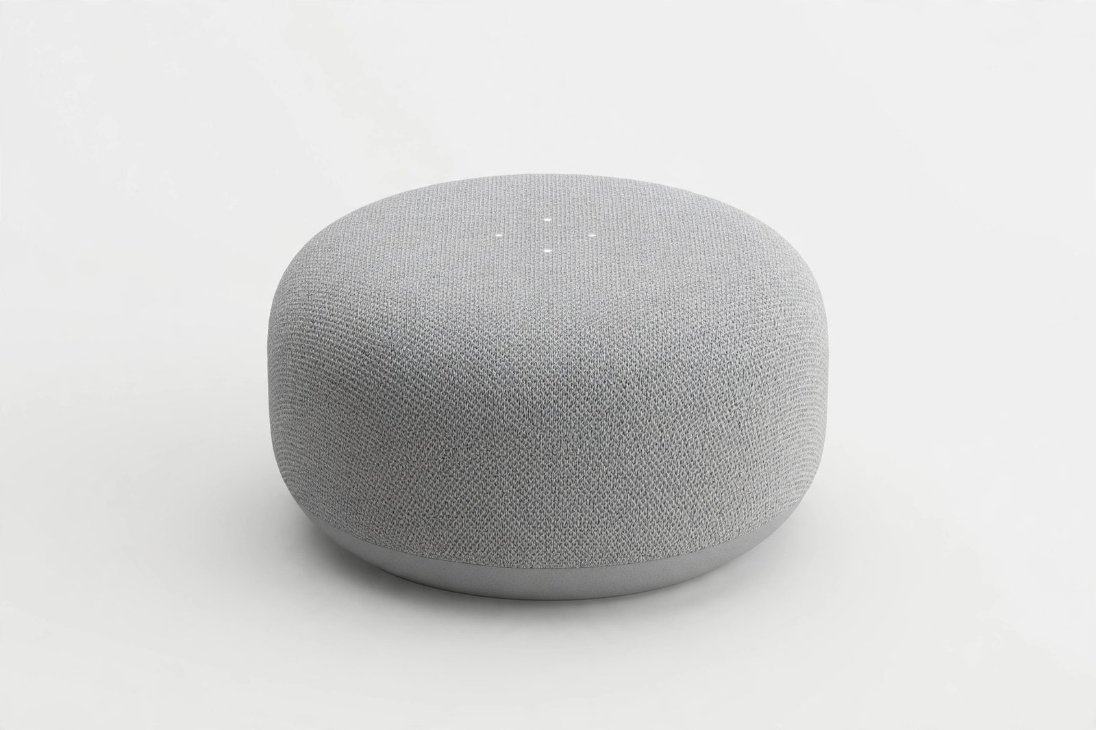 Compact round smart speaker with a fabric mesh finish on a light background
