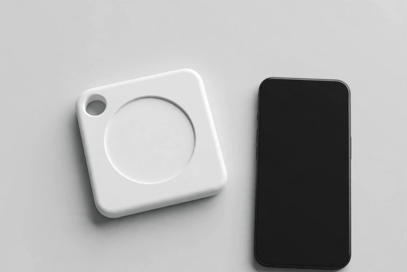 Tile Mate 2024 Bluetooth tracker, a small square tag with rounded corners and a keyring hole, shown next to a smartphone